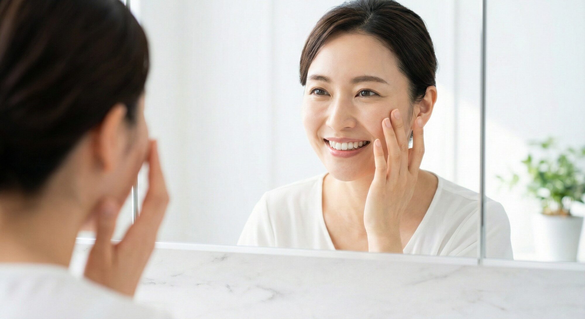 クマ取り注射の効果を実感し、明るい目元を鏡で確認して笑顔になる30代女性